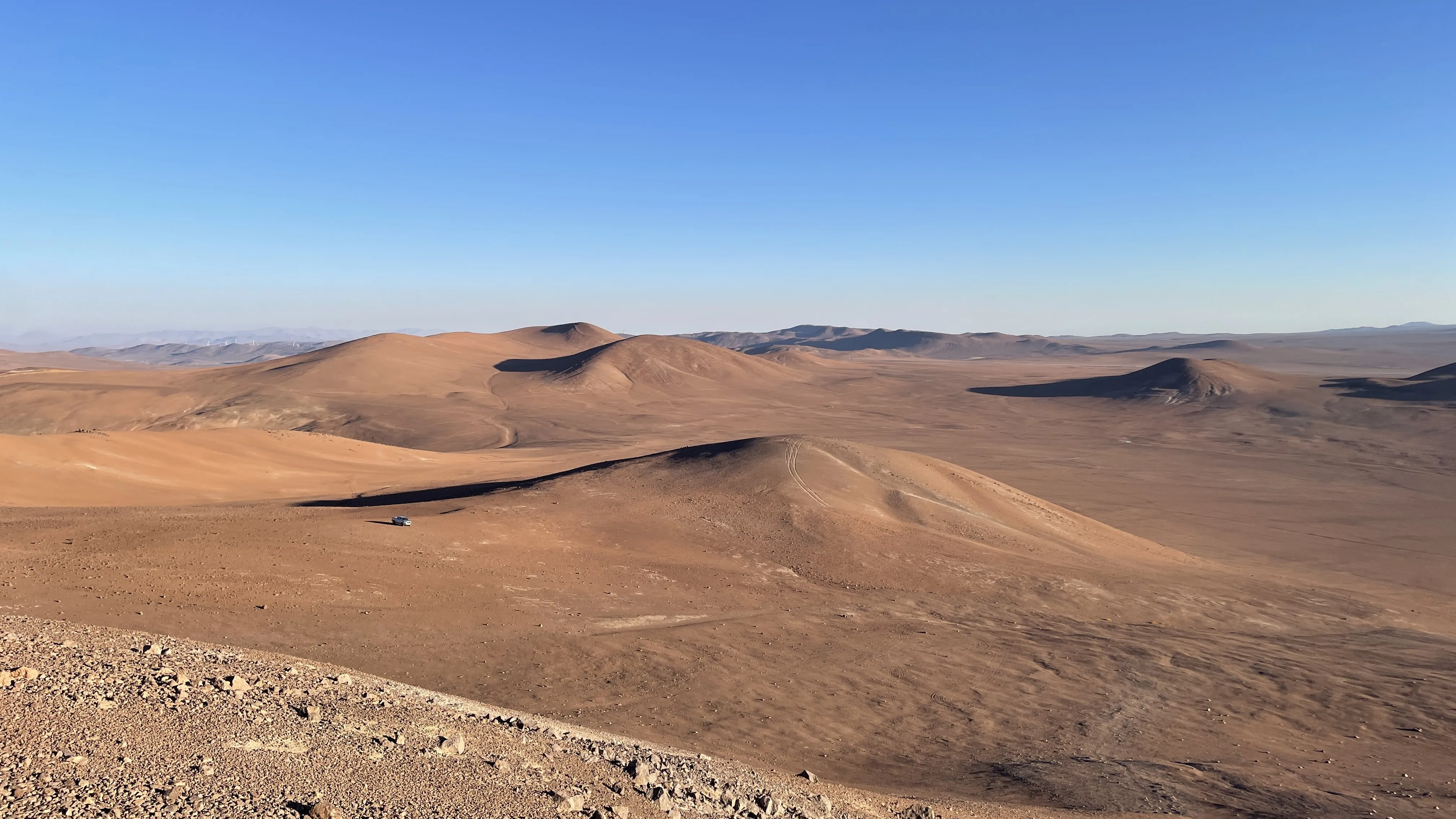 Vista panorámica del Desierto de Atacama con un vehículo de expedición a lo lejos